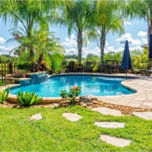 The Fermentum Tellus: A backyard oasis complete with a pool, palm trees, lush greenery, lounge chairs, an umbrella nearby, and a stone path leading to the refreshing waters.